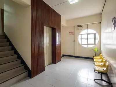 a hallway with yellow chairs and stairs in a building at Muangphol Mansion in Bangkok
