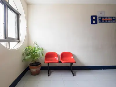 a room with two red chairs and a potted plant at Muangphol Mansion in Bangkok