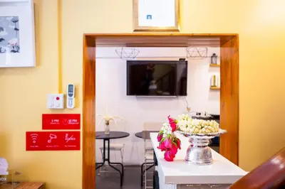a room with a table with a vase of flowers at OYO 895 The Onion Hostel in Bangkok