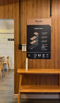 a sign on a wall above a wooden bench at Hyde Residence Ladprao48 in Bangkok