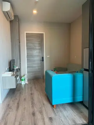 a living room with a blue couch in front of a door at KnIGHTSBRIDGE in Bangkok
