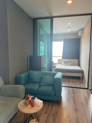 a living room with a blue couch and a bed at KnIGHTSBRIDGE in Bangkok