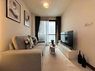 a living room with a couch and a flat screen tv at Stylish Low-rise 1BR - Ultra Fast WiFi - BTS Thonglor in Bangkok