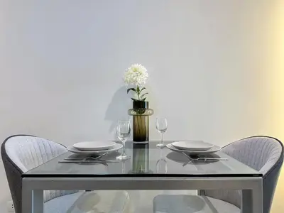 a glass table with two chairs and a vase with flowers at Stylish Low-rise 1BR - Ultra Fast WiFi - BTS Thonglor in Bangkok