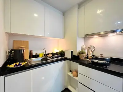 a kitchen with white cabinets and a sink at Stylish Low-rise 1BR - Ultra Fast WiFi - BTS Thonglor in Bangkok