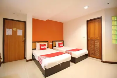 two beds in a room with orange walls at Pannee Lodge Khaosan - SHA Plus in Bangkok
