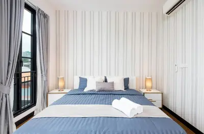 a bedroom with a large blue bed with two lamps at Stylish 7Beds Poolhouse with Cinema Lift - 2min to BTS in Amphoe Phra Khanong