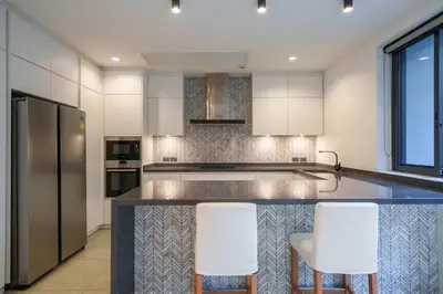 a kitchen with a counter and two white stools at MonochromeDesignerPool Villa in Bangkok