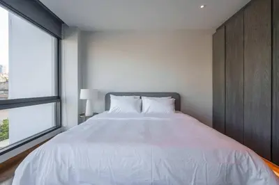 a bedroom with a large white bed and a window at MonochromeDesignerPool Villa in Bangkok