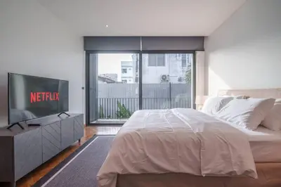 a bedroom with a bed and a tv and a window at MonochromeDesignerPool Villa in Bangkok