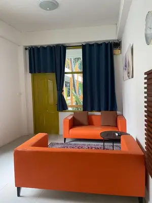 an orange couch in a living room with a window at Happy 2 Hotel Patunam in Bangkok