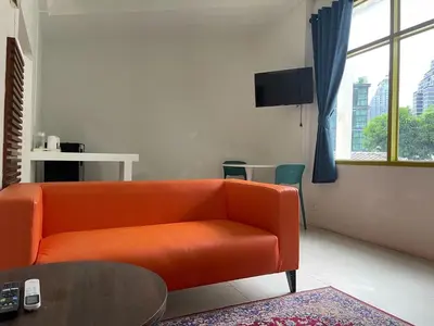 a living room with an orange couch and a table at Happy 2 Hotel Patunam in Bangkok