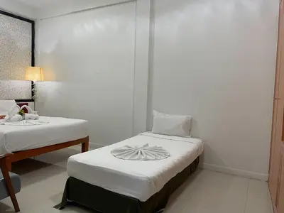 a small room with two beds and a table at Happy 2 Hotel Patunam in Bangkok