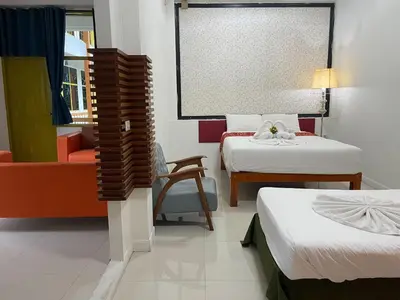 a hotel room with two beds and a chair at Happy 2 Hotel Patunam in Bangkok