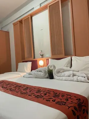two beds in a hotel room with towels on them at Happy 2 Hotel Patunam in Bangkok
