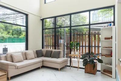 a living room with a couch and large windows at Shizuka House - 500 m walk to BTS Phrom Phong in Bangkok
