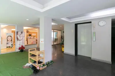 a person laying on a green rug in a room with a clock at Resortel Lat Phrao 91 in Bangkok