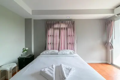 a bedroom with a white bed with a pink window at Resortel Lat Phrao 91 in Bangkok