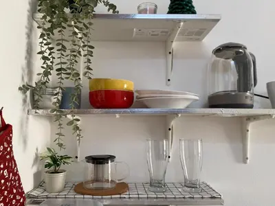 a shelf with dishes and glasses on it at Tiny Nest Pratunum Airport Link in Pratunam
