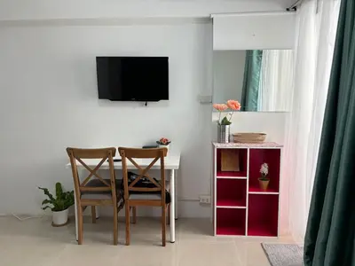 a dining room with a table and two chairs and a tv at Tiny Nest Pratunum Airport Link in Pratunam
