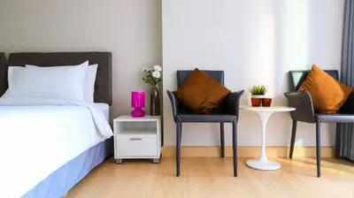 a bedroom with two chairs and a bed and a table at CU iHouse เรือนวิรัชมิตร in Bang Rak