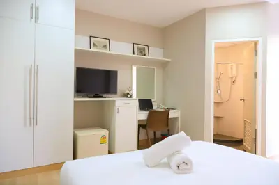a bedroom with a bed and a desk with a computer at CU iHouse เรือนวิรัชมิตร in Bang Rak
