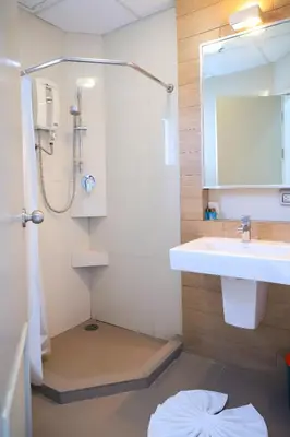 a bathroom with a shower and a sink and a mirror at CU iHouse เรือนวิรัชมิตร in Bang Rak