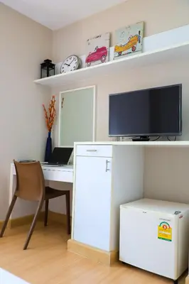 a room with a desk with a computer and a tv at CU iHouse เรือนวิรัชมิตร in Bang Rak