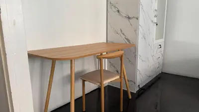 a wooden table and a stool next to a wall at Cozy Cat Souluna home in Ekkamai in Bangkok