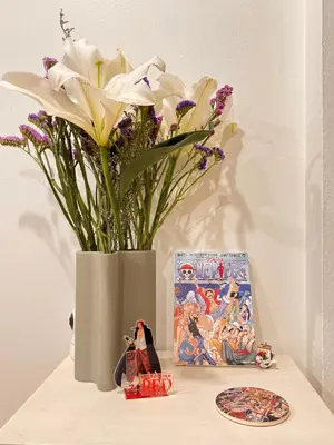 a vase with flowers sitting on a table next to a plate at Cozy Cat Souluna home in Ekkamai in Bangkok
