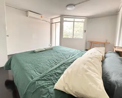 a bedroom with a green bed and a window at Cozy Cat Souluna home in Ekkamai in Bangkok