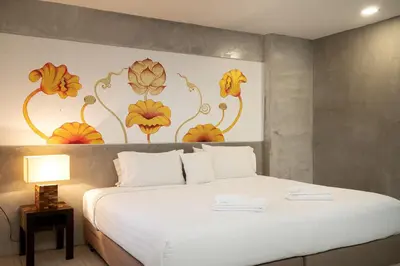 a bedroom with a white bed with a flower mural on the wall at The Riche Boutique Hotel Don Mueang Airport in Bangkok