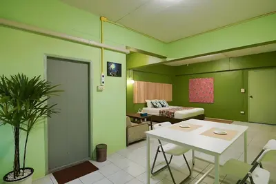 a room with green walls and a table and a bed at XX GO INN The Grand Palace - MRT Samyot Station in Bangkok