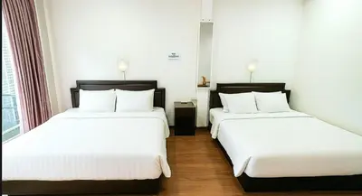 two beds in a hotel room with white sheets at Asia Mahanakhorn Travel in Bangkok