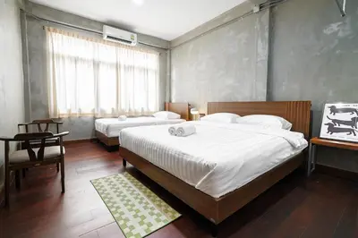 a bedroom with two beds and a table and a window at Siam Breeze Inn - Self Check-in in Bangkok