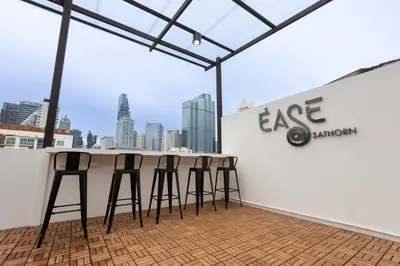 a bar with four stools in front of a wall at Ease at Sathorn Hostel and Coworking Space in Bangkok