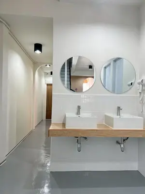 a bathroom with two sinks and two mirrors at Ease at Sathorn Hostel and Coworking Space in Bangkok
