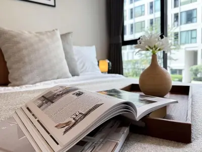 a magazine on a table next to a bed at Stylish Tropical l 2BR - Ultra Fast Wifi - Sathorn in Bangkok