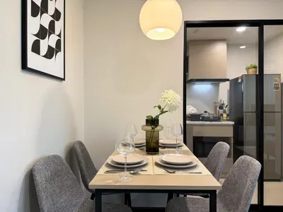 a dining room with a table with chairs and a kitchen at Stylish Tropical l 2BR - Ultra Fast Wifi - Sathorn in Bangkok
