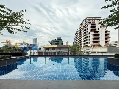 a large swimming pool in a city with buildings at Transquil Modern 1BR - Ultra Fast WiFi - BTS Ari in Bangkok