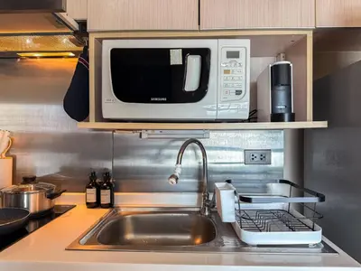 a microwave oven sitting above a sink in a kitchen at Tropical Modern 1BR - Ultra Fast Wifi - Thong Lo in Bangkok