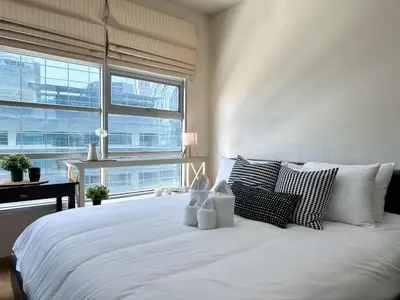 a white bed with pillows and a desk in a bedroom at Centralized High-Rise - Ultra Fast Wifi - Ratchathewi in Bangkok