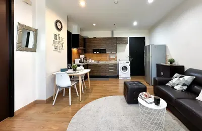a living room with a couch and a kitchen at Centralized High-Rise - Ultra Fast Wifi - Ratchathewi in Bangkok