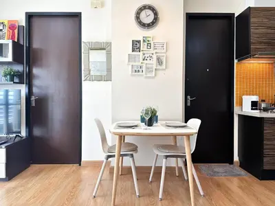 a table and chairs in a kitchen with a clock on the wall at Centralized High-Rise - Ultra Fast Wifi - Ratchathewi in Bangkok