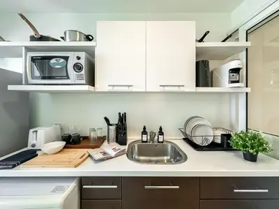 a kitchen counter with a sink and a microwave at Contemporary Modern 1BR - Ultra Fast WiFi - On nut in Bangkok