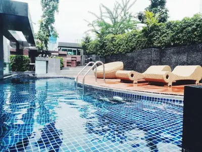 a swimming pool with lounge chairs next to a building at Expansive Premier 1BR - Ultra Fast Wifi - Phrom Phong in Bangkok