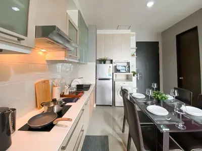 a kitchen with a dining table and a refrigerator at Upscale Modern 2BR - Ultra Fast WiFi - BTS Asoke in Bangkok