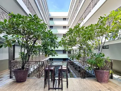a balcony with chairs and trees in a building at Stylish Exquisite 1BR in Bangkok