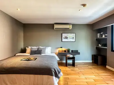 a bedroom with a bed and a table with a fan at Stylish Exquisite 1BR in Bangkok