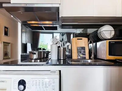 a kitchen with a microwave and a stove top oven at Ruamrudee Modern - Ultra Fast WiFi - BTS Ploenchit in Bangkok